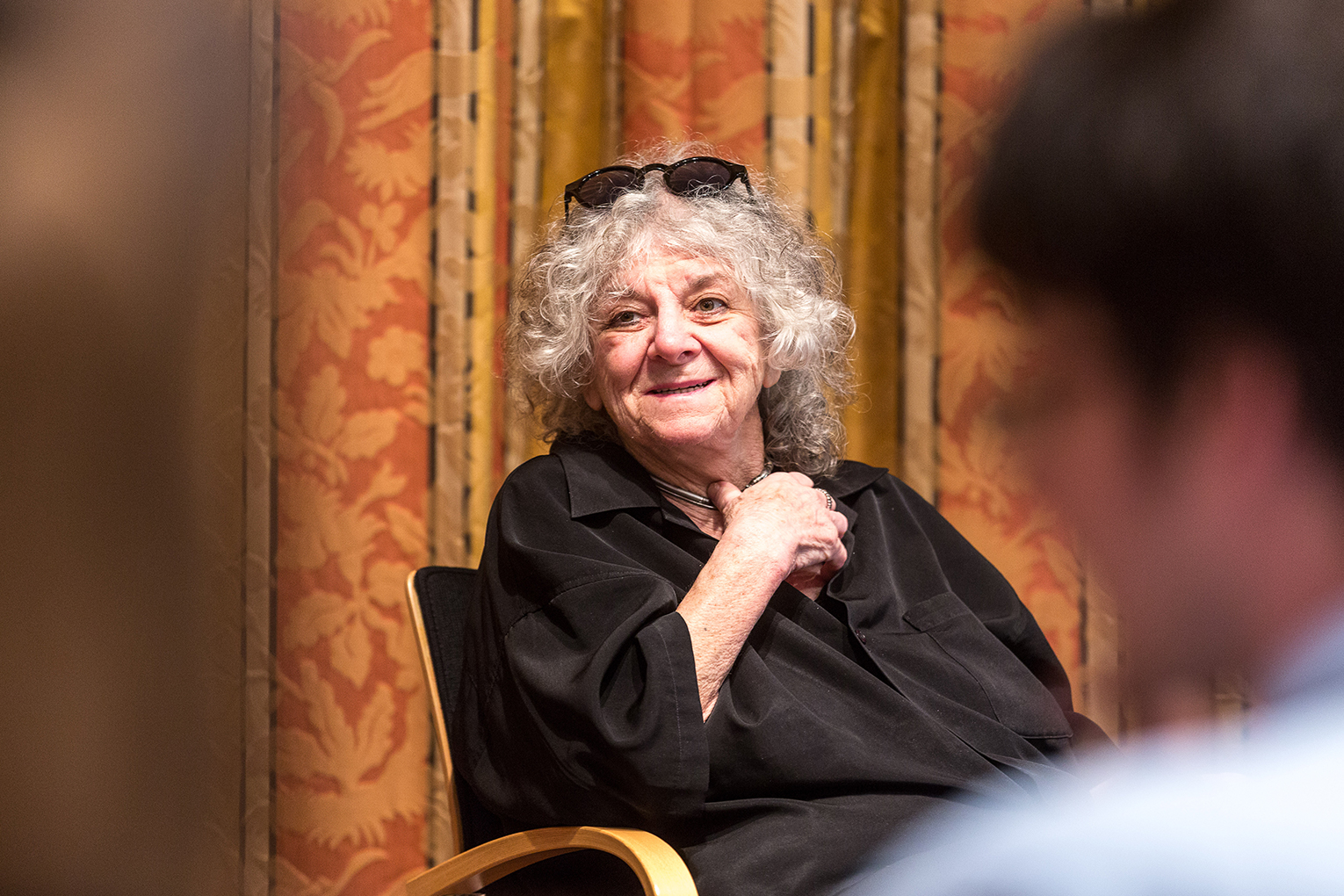 Ada Yonath in a black blouse and sunglasses in her hair listens to young scientists in Lindau